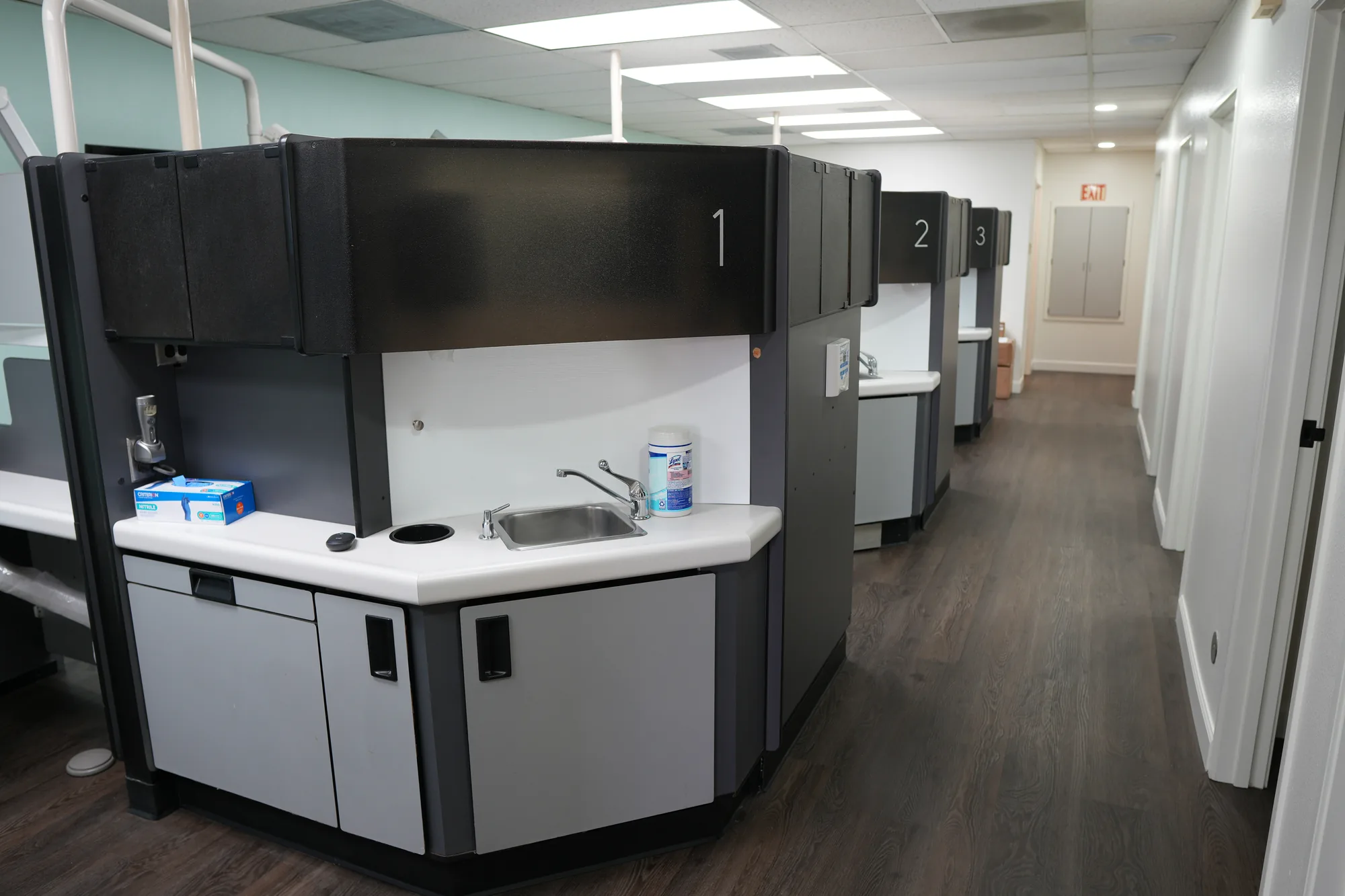 Hallway lined with numbered treatment bays with counters and sinks