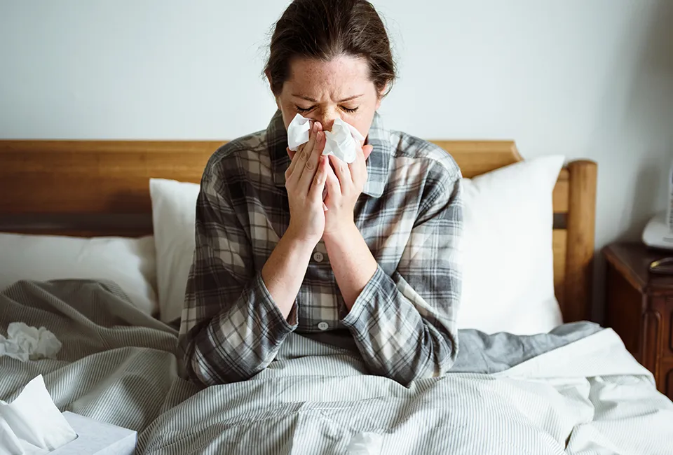 A person blowing her nose in a tissue